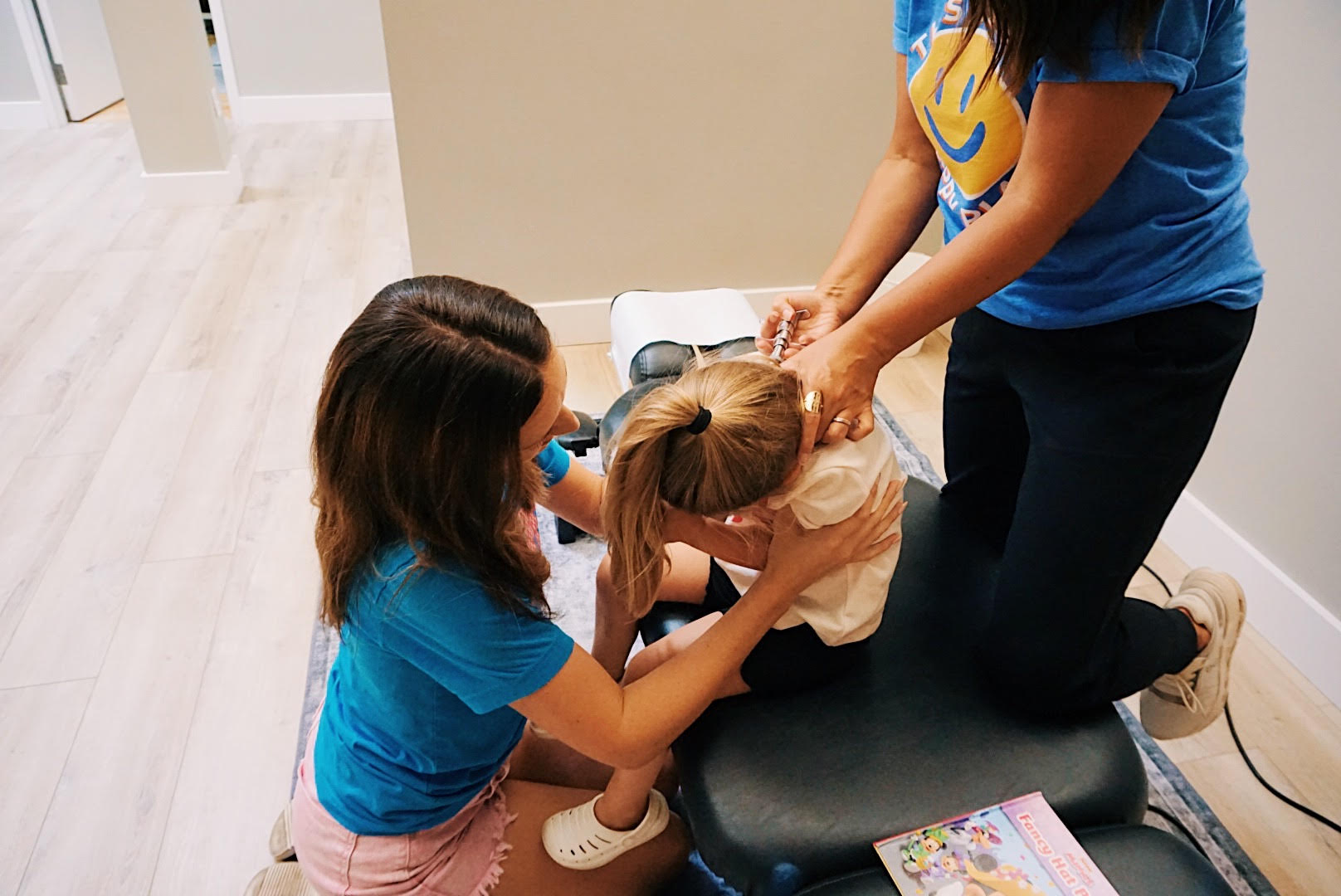 Dr. Maggie Hunsicker and Dr. Kailee Logan providing gentle family chiropractic care to child patient at Thrive Chiropractic in Topeka KS